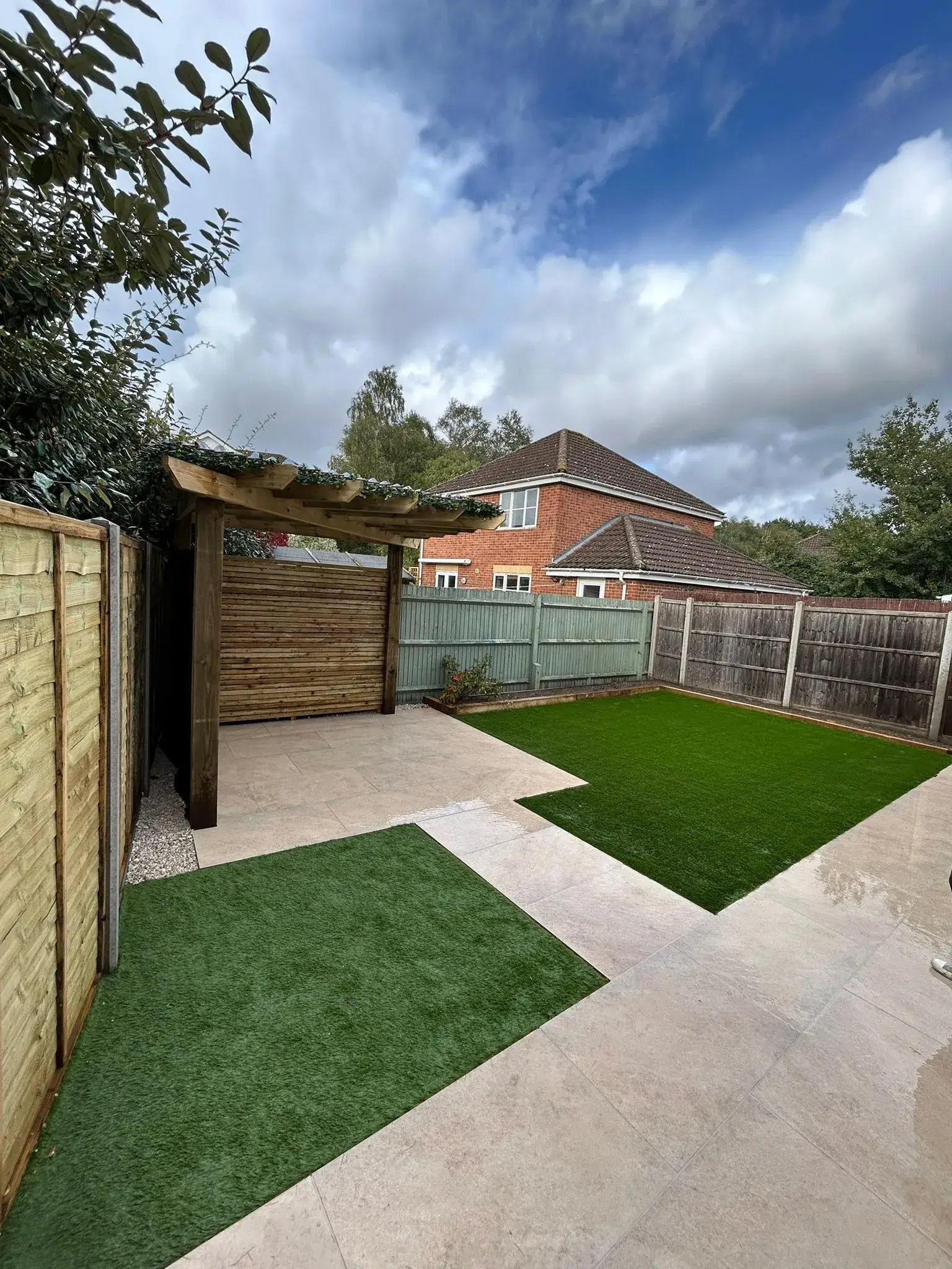 A backyard with artificial grass and a wooden fence.