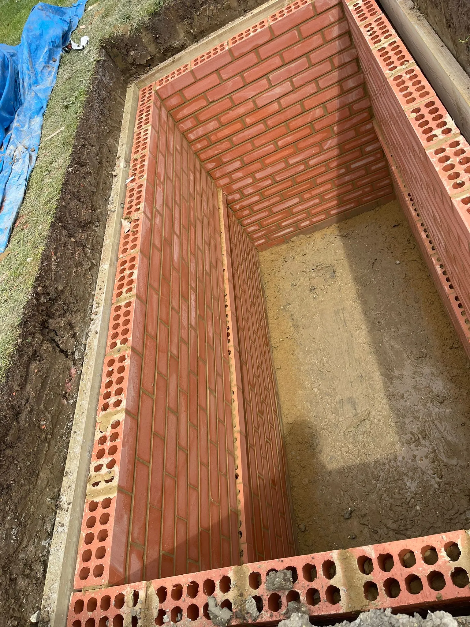 A red brick laying on top of a pile of dirt.